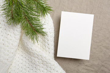 Christmas greeting card mockup with pine tree branch on white knitted background