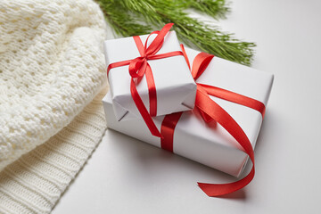 Christmas gift boxes with red ribbon and knitted sweater with green pine tree branches on white