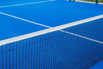 Net and serving lines of a blue paddle tennis court