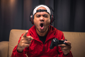 Angry asian gamer man. He lose in the game. Missed the chance to become a champion in tournament. Unhappy upset Indian streaming video game online and lost. © Chanakon