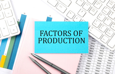 FACTORS OF PRODUCTION text on blue sticker on chart with calculator and keyboard