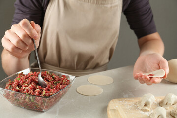 Woman putting gyoza filling in center of dough wrapper at light table, closeup