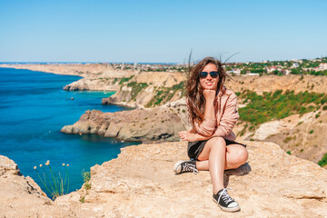 A young beautiful woman travels to Cape Fiolent, the most famous place in Crimea with an azure wave and rocks