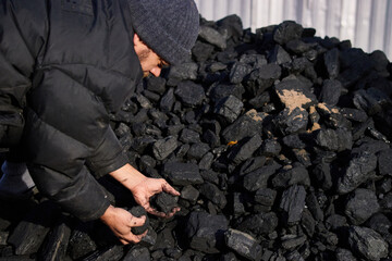 poor middle-aged man holding the hands of stone coal for sale to provide food for his family