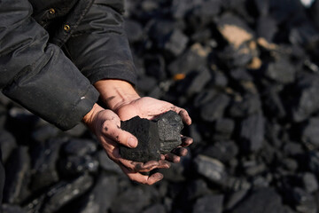 poor middle-aged man holding the hands of stone coal for sale to provide food for his family