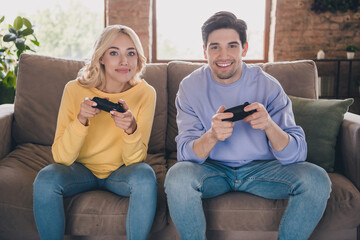 Photo of young couple girlfriend boyfriend play game joystick sit sofa spend weekend together indoors