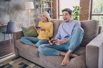 Obraz premium Photo of beautiful excited young lovers dressed casual clothes sitting sofa holding playstation smiling indoors apartment