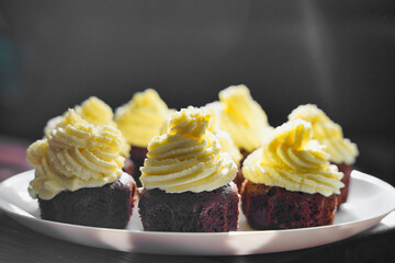 Chocolate cupcakes with yellow butter cream, homemade, on a plate in hands