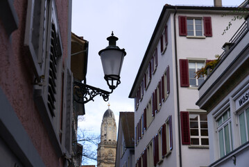 Fototapeta na wymiar Historic medieval alley at the old town of Zürich with protestant church tower of Great Minster on a cloudy autumn day. Photo taken October 26th, 2021, Zurich, Switzerland.
