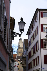 Fototapeta na wymiar Historic medieval alley at the old town of Zürich with protestant church tower of Great Minster on a cloudy autumn day. Photo taken October 26th, 2021, Zurich, Switzerland.