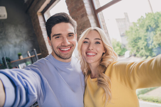 Self-portrait of attractive trendy cheerful couple staying spending free time at home loft industrial interior indoors