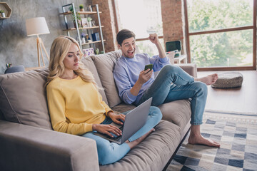 Obraz premium Portrait of handsome beautiful trendy cheerful couple using gadget laptop pastime on divan at home loft industrial interior indoors