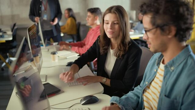 Diverse Multiethnic Group of Female and Male Students Sitting in College Room, Collaborating on School Projects on a Computer. Young Scholars Study, Talk, Apply Academic Skills and Knowledge in Class.