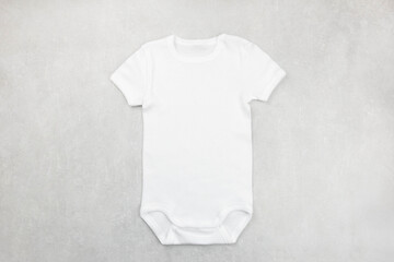 White baby girl or boy bodysuit mockup flat lay on the gray concrete background. Design onesie...