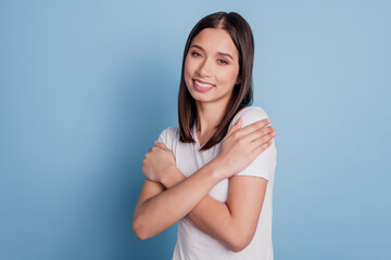 Fototapeta premium Photo of pretty cute relaxed lady hug shoulders enjoy toothy beaming smile on blue background