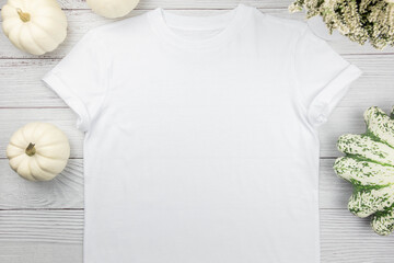 White womens cotton t-shirt mockup with pumpkins on white wooden background. Design t shirt...