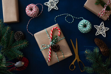 wrapping of Christmas gifts in eco-style craft paper and natural materials, fir branches on a blue wooden background.