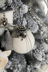 Close up of white-gray Christmas tree with toys, garlands, and holidays hat