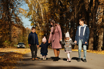 Mother with four kids in autumn park. Family walk in fall forest.