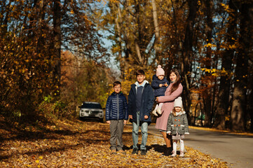 Mother with four kids in autumn park. Family walk in fall forest.