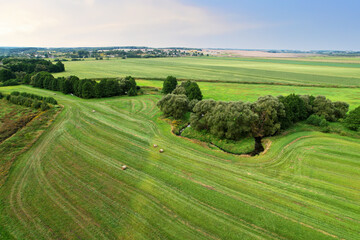 River in the wild. Aerial view of small river in middle of green field and forest in the...