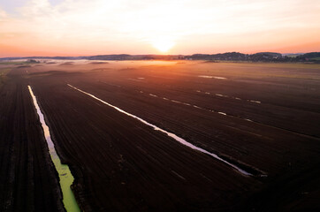 Peat extraction site in fog on sunset. Collecting peat on peatlands. Mining and harvesting...