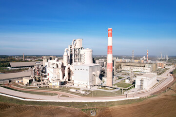 Obraz premium Cement plant with pipes. Сement production process and Industrial solution. factory with smoke pipe. Chimney smokestack emission. Poor environment. Ecology concept, air and environmental pollution.