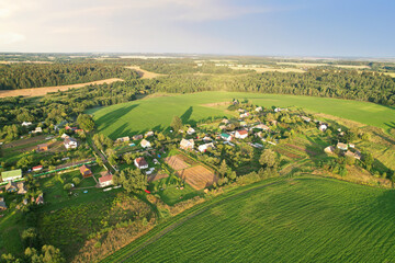 Country houses in the countryside. Aerial view of roofs of green field with rural homes. Village with wooden home. Suburban house at farm. Housing outside the city. Agriculture, farming and agronomy.