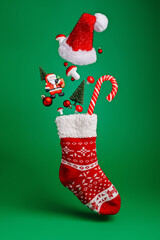 Creative layout made with flying Christmas socks, Santa Claus, pine tree and candy cane on green background. Minimal New Year season concept. Winter holidays idea.