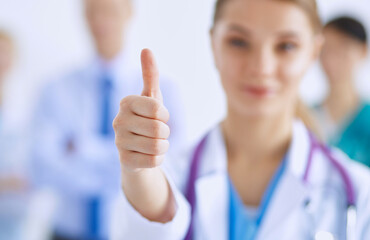 Young happy female doctor showing thumbs up