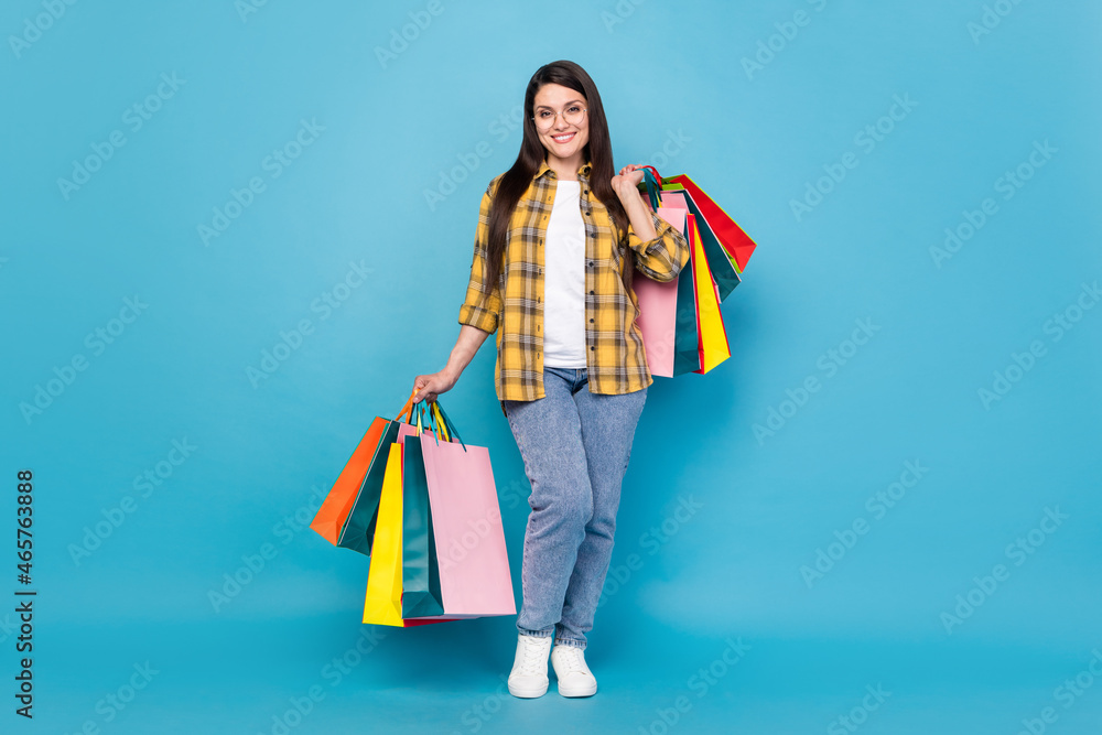 Sticker Full length body size view of attractive cheerful girl holding new things bags bargain isolated over bright blue color background