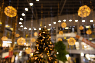 Shopping mall preparing for Christmas holidays indoor unfocused photography with yellow and golden garland and decoration illuminated objects