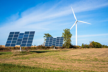 Solar panels and a wind turbine in a field under blue sky. Copy space. Renewable energy concept.