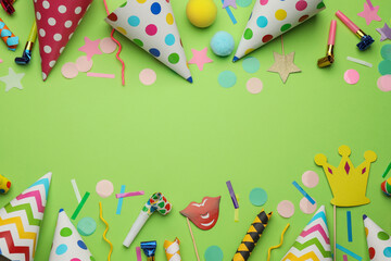 Flat lay composition with party hats and other festive items on light green background. Space for...