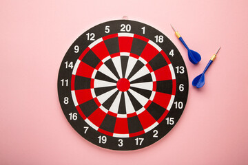 Dart board with blue darts on pink background.