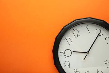 Black wall clock on the orange background.