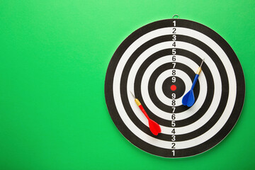 Dart board with blue and red darts on green background.