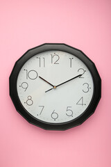 Black wall clock on the pink background.