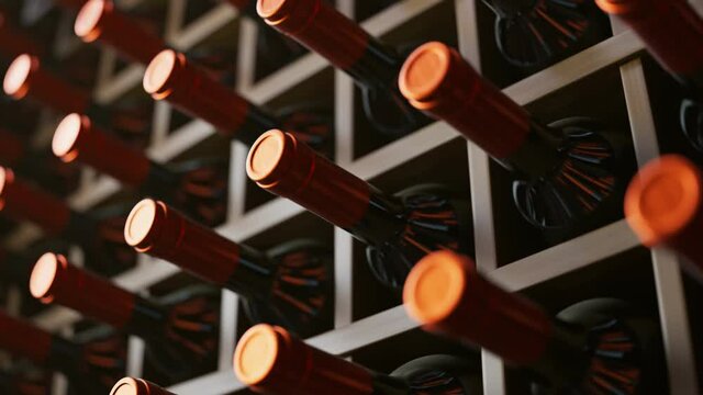 Looping animation of wine bottles ordered on wooden shelves in dark wine-cellar.