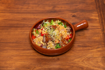 Asian beef stew with vegetables, rice and lettuce with bean sprouts in a nice clay pan