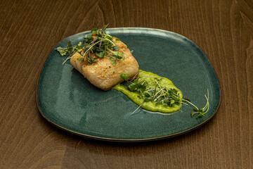 Delicious dish of stewed hake with paprika and tender lettuce shoots on a green plate