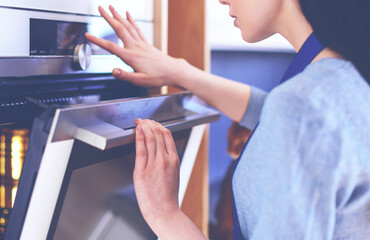 Obraz premium Beautiful young woman checking how her cake is doing in the oven