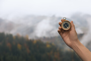 Woman using compass during journey in mountains, closeup. Space for text