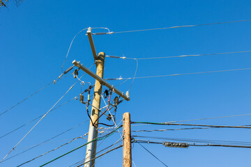 Power line infrastructure and transformer on a pole against a blue sky