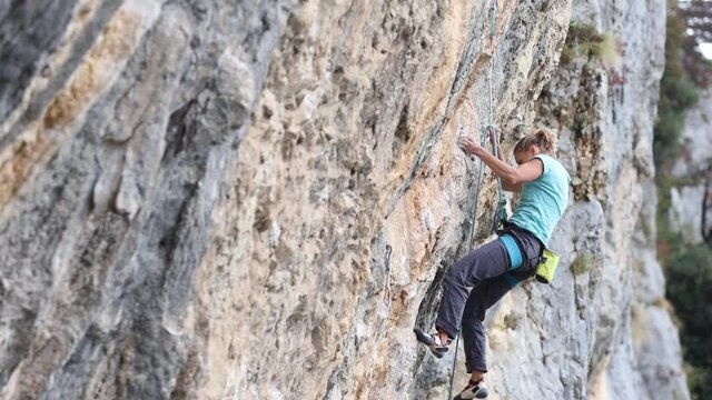The girl climbs the rock. The climber trains on natural terrain. Extreme sport. Outdoor activities. A woman overcomes a difficult route rock climbing in Croatia area Kompanj 