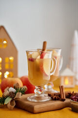 Alcohol apple white mulled wine with cardamom, cinnamon and cranberry. Winter Christmas grog. Selective focus, blurred background with xmas decorations bokeh, copy space, vertical