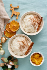 Christmas food. Rice pudding. French milk rice dessert. Two bowl. of healthy Vegan diet breakfast with coconut milk, cinnamon. Color linen textile, Christmas decoration. Copy space, vertical, top view