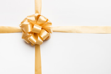 Fototapeta premium Top view of gold ribbon rolled and yellowbow isolated on colored background. Flat lay with copy space