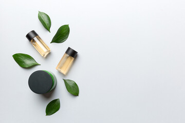 Organic cosmetic products with green leaves on color background. Copy space, flat lay