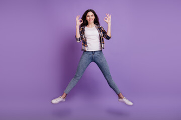Fototapeta na wymiar Full size photo of young attractive girl happy positive smile jump up show okay alright sign isolated over violet color background